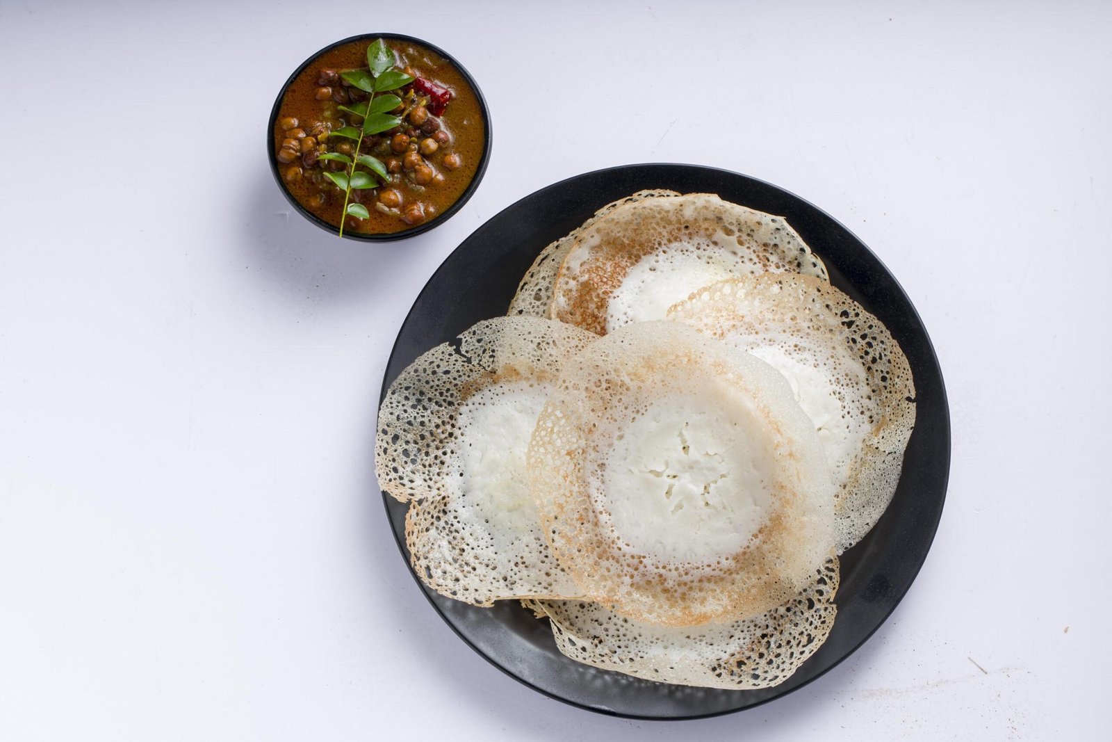 Appam or velliappam or kallappam  or paalappam, tasty delicious  breakfast item in south india and with a good combination of kadala curry or bengal gram curry ,placed on a white background.